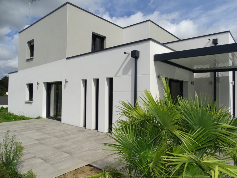 Maison moderne à l'architecture épurée avec terrasse et végétation environnante.
