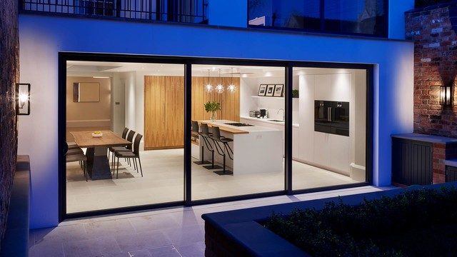 Vue d'une cuisine moderne avec une grande baie vitrée donnant sur un jardin.