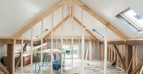 Intérieur d'une pièce en cours de rénovation avec poutres en bois et outils de construction.